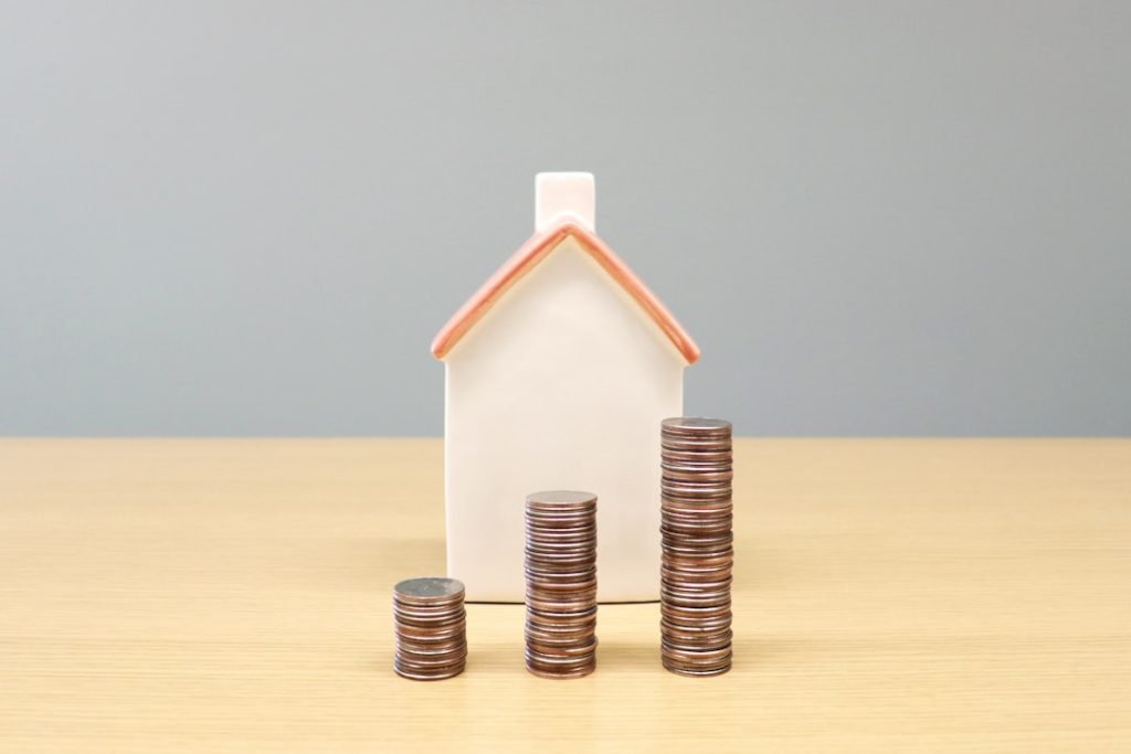 a-house-and-stacks-of-coins-on-a-table-uft0gythnve